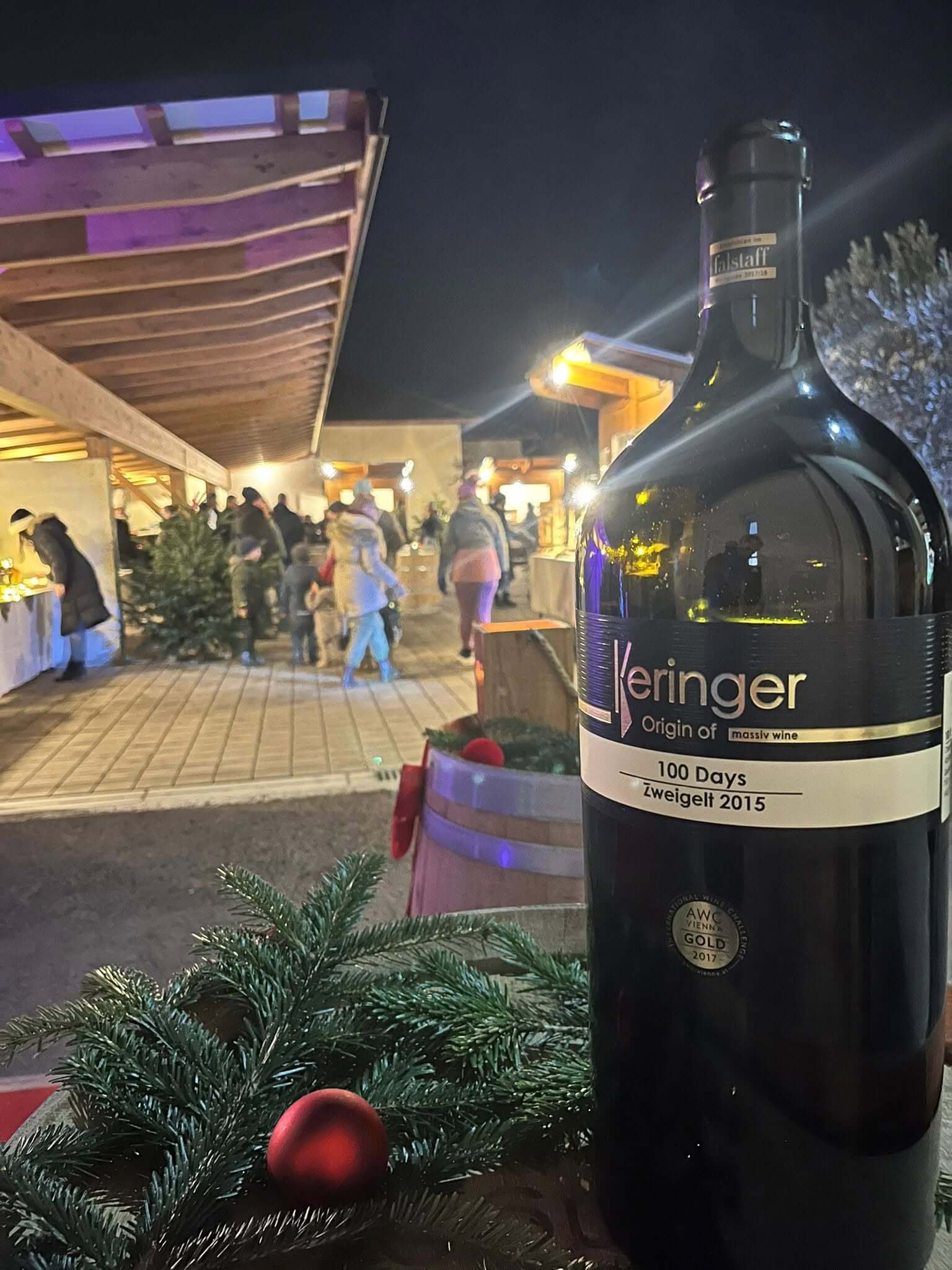 100 DAYS Zweigelt 2015 Flaschenfoto mit Gästen im Hintergrund im Rahmen der Veranstaltung Advent by Keringer