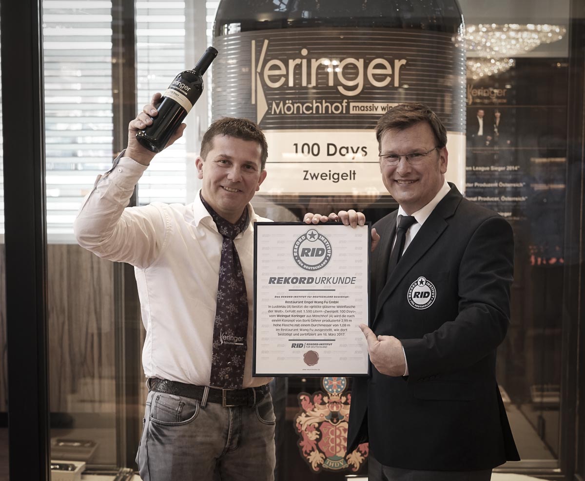 Robert Keringer mit Weltrekord Urkunde vor der größten Weinflasche der Welt